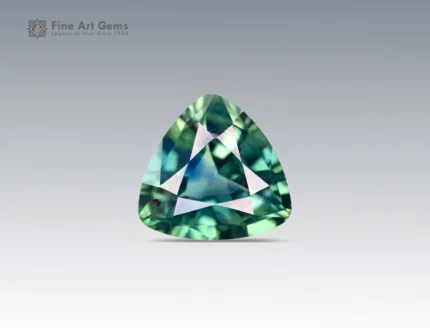 Trilliant cut 1.5 carat sapphire gemstone from Nigeria showing green and blue hues on a neutral background