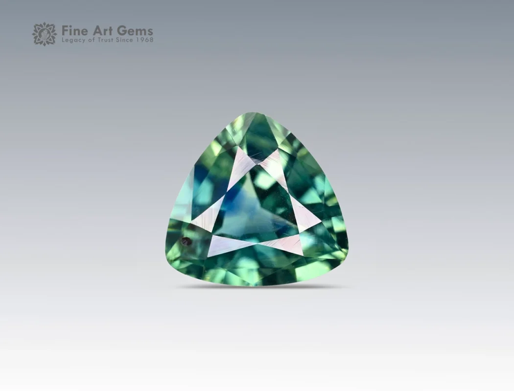 Trilliant cut 1.5 carat sapphire gemstone from Nigeria showing green and blue hues on a neutral background