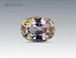 A 1.3 carat oval-cut Parti Sapphire from Nigeria showing mixed shades of green, yellow, and violet tones, ideal for jewelry.